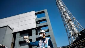 Un employé de Tepco mesure le niveau de radiations devant le réacteur n°4 de la centrale de Fukushima, le 21 février 2021 au Japon