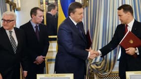 Le président ukrainien Viktor Ianoukovitch (à gauche) et le ministre polonais des affaires étrangères Radoslaw Sikorski (à droite) se serrent la main. .