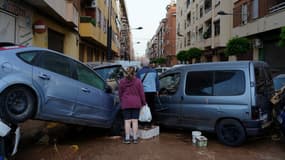 Des habitants se tiennent devant des voitures empilées à la suite d'inondations meurtrières dans le quartier d'Alfafar, au sud de Valence, le 30 octobre 2024.
