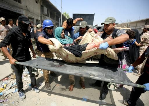 Des membres des forces de sécurité irakiennes transportent une femme blessée lorsqu'un kamikaze s'est fait exploser, le 23 juin 2017 à Mossoul