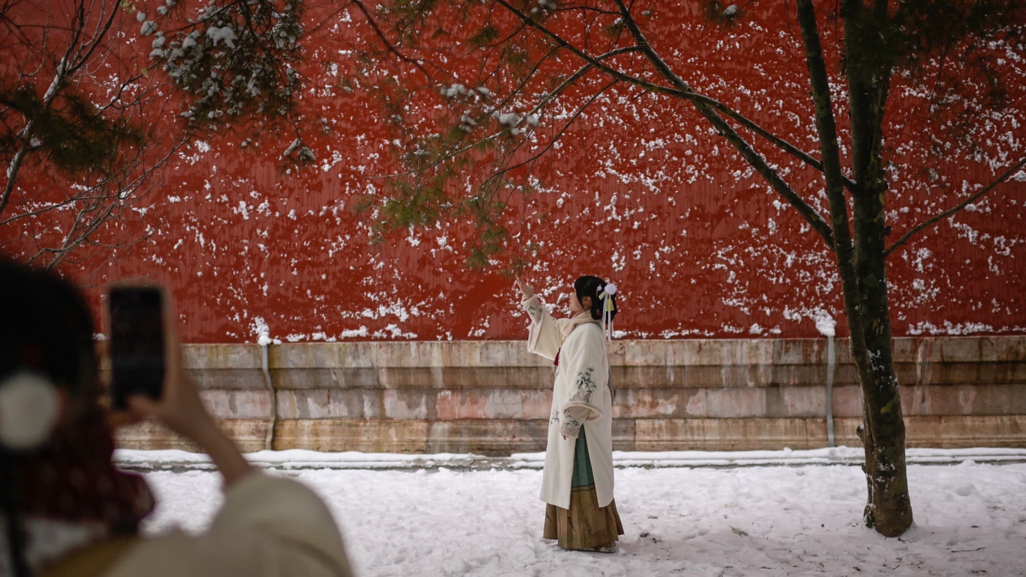Une femme portant un costume traditionnel pose à la Cité interdite un jour après une chute de neige à Pékin le 21 février 2024.