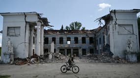 Un homme roule à vélo devant un bâtiment détruit à Druzhkivka, dans la région de Donetsk, le 15 août 2025, en pleine invasion russe de l'Ukraine.