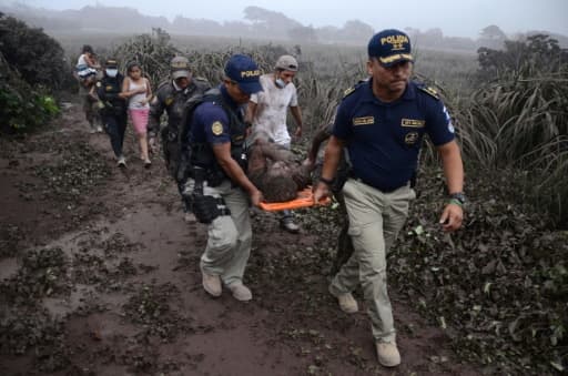 Des policiers évacuent un blessé lors de l'érruption du volcan Fuego, dans le village d'El Rodeo village, à 35 km au sud de la ville Guatemala le 3 juin 2018 Des policiers évacuent un blessé lors de l'érruption du volcan Fuego, dans le village d'El Rodeo village, à 35 km au sud de la ville Guatemala le 3 juin 2018