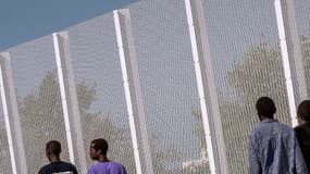 Des migrants marchent à côté d'une clôture bordant la Jungle, à Calais, le 8 septembre 2016.