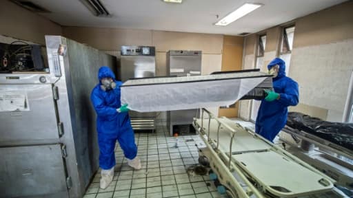 Des employés de Los Olivos Funerales en combinaison intégrale de protection transportent du corps d'une personne décédée du coronavirus, le 1er juin 2020 à Mexico