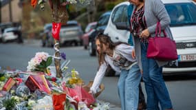 Une jeune fille dépose des fleurs sur le site où une voiture a foncé dans une foule de carnavaliers tôt le matin du 20 mars, à Strepy-Bracquegnies, La Louvière, le 22 mars 2022.
