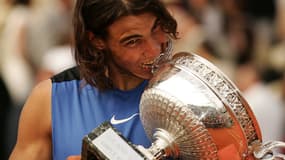 Rafael Nadal mordant la coupe des Mousquetaires lors de sa deuxième victoire sur Roland-Garros en 2006.  