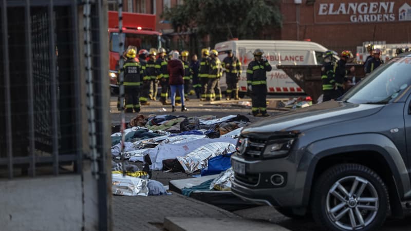 Des corps recouverts de couvertures et de draps sont visibles sur la scène d'un incendie à Johannesburg le 31 août 2023.