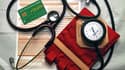 Une feuille de soins, une carte d'assurance maladie, un stétoscope et un tensiomètre dans un cabinet médical (image d'illustration)