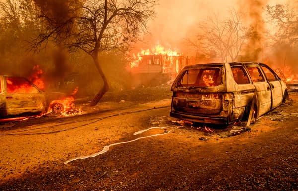 Des voitures brûlées alors les flammes engloutissent une maison à Oroville, en Californie, aux États-Unis, le 2 juillet 2024.