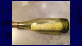Capture d'écran du compte Facebook personnel de Fabrice Léveillé, collectionneur d'objets anciens à l'origine de la découverte. Sur l'image, on aperçoit une bouteille de vin en verre dans laquelle se trouve un petit mot écrit à la main sur une feuille de papier. 