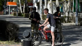 Un civil à vélo passe devant des soldats russes à Skadovsk, dans l'Oblast de Kherson Oblast, le 20 mai 2022