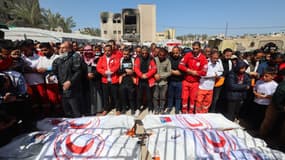 Des membres du Croissant Rouge palestinien et d'autres services d'urgence prient près des corps de leurs collègues secouristes tués une semaine plus tôt par les forces israéliennes, à Khan Younès, dans le sud de la bande de Gaza, le 31 mars 2025. 