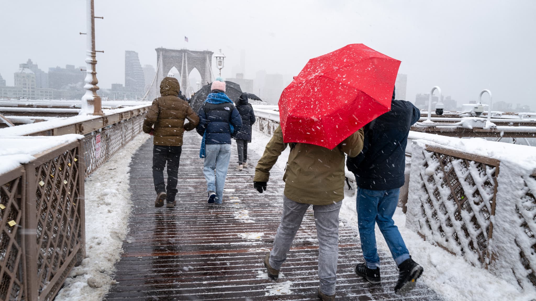 Des personnes traversent le pont de Brooklyn, à Manhattan, alors qu'une grosse tempête hivernale traverse la région le 13 février 2024 à New York. 