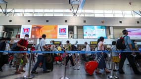 Des passagers masqués font la queue au terminal des départs de l'aéroport international de Danang, à Danang, le 27 juillet 2020.