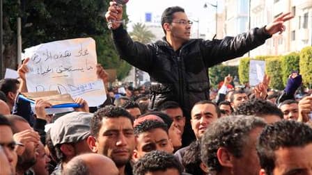 Un homme, à Tunis, avec un sèche-cheveu en référence à l'ex-première dame de Tunisie Leïla Trabilsi lors d'une manifestation appelant à former un gouvernement sans membres ayant officié sous le régime de Zine Ben Ali. La télévision locale a en outre annon