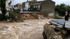 Des habitants se tiennent devant ce qui était auparavant un pont à Villegailhenc, dans l'Aude, après de violentes inondations le 15 octobre 2018.