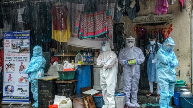 Des soignants en combinaison de protection s'abritent de la pluie à Bombay (Inde) le 12 août 2020.