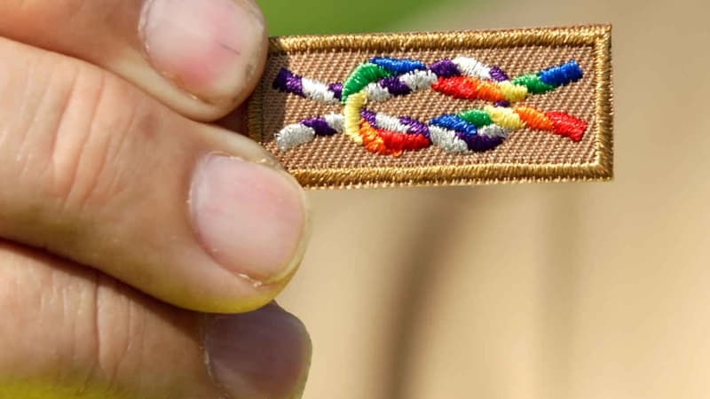 Un membre des "scouts pour l'égalité" montre un insigne liant les symboles scouts et celui des droits des homosexuels.