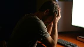 Une personne triste devant son ordinateur.