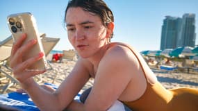 Une jeune fille à la plage avec son smartphone.