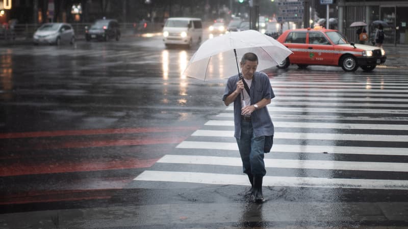 Un homme se protège de la pluie à Tokyo, le 28 juillet 2018, à l'approche du typhon Jongdari.