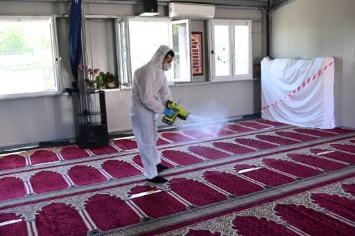 Un homme désinfecte des tapis après la prière du vendredi dans une mosquée de Milan, le 5 juin 2020 Un homme désinfecte des tapis après la prière du vendredi dans une mosquée de Milan, le 5 juin 2020