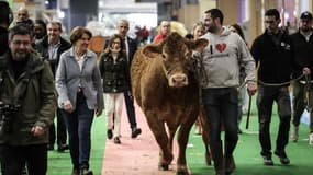 L'éleveur Alexandre Humeau marche avec sa vache limousine Oupette aux côtés de la la ministre de l'Agriculture, Annie Genevard, le 21 février 2025 à la veille de l'ouverture du 61ème Salon international de l'agriculture (SIA) à Paris.