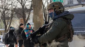 Un agent fédéral de l'immigration américaine face à des habitants de Minneapolis protestant contre la présence de l'ICE dans la ville, ce samedi 24 janvier.