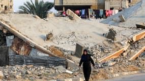 Une femme passe devant les décombres d'un bâtiment effondré dans un camp pour personnes déplacées par le conflit à Bureij, dans le centre de la bande de Gaza, le 17 janvier 2025, après l'annonce d'une trêve dans le contexte de la guerre en cours entre Israël et le Hamas.
