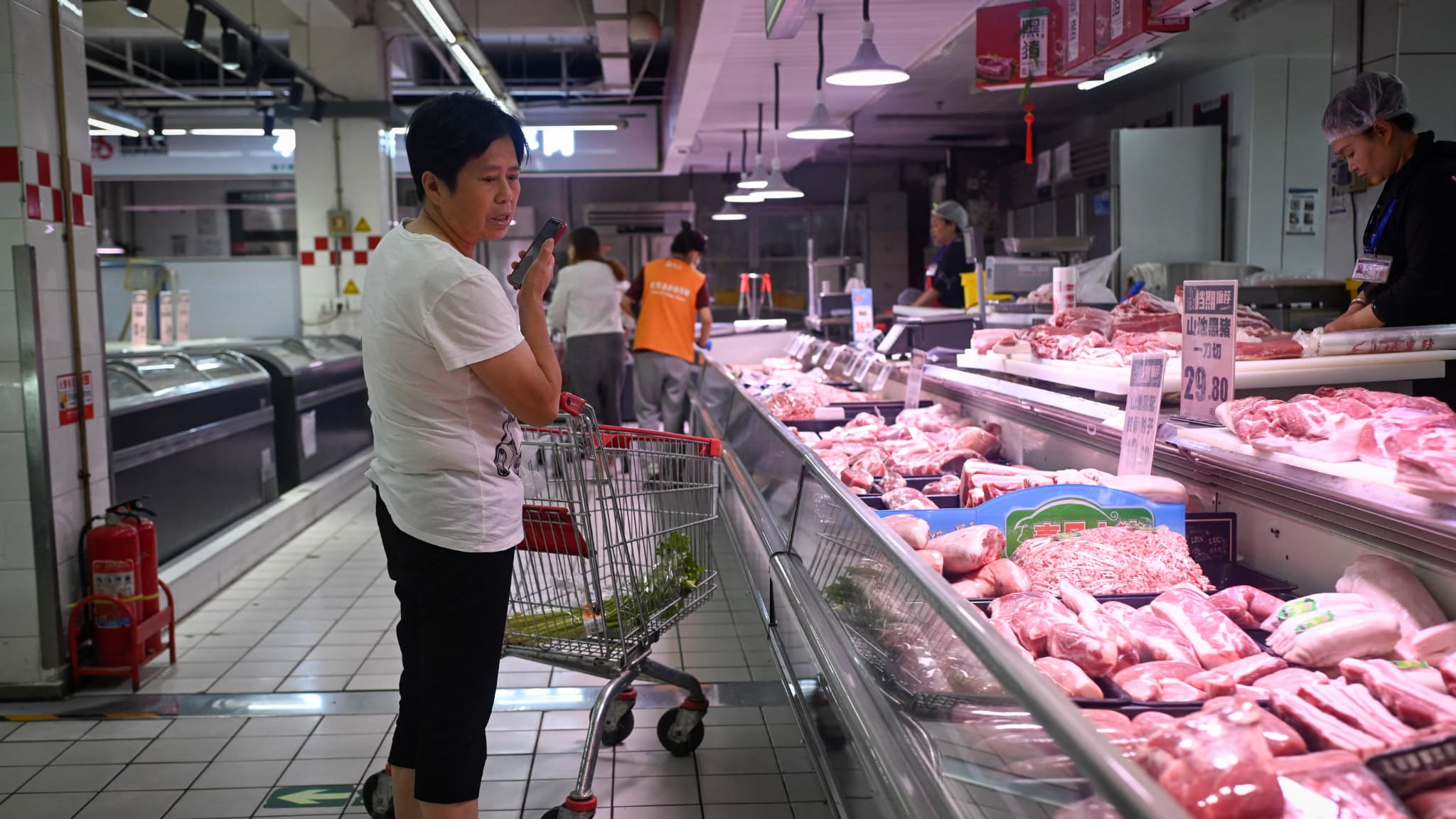Une femme choisit des produits à base de porc dans un supermarché de Pékin, le 12 juin 2024.