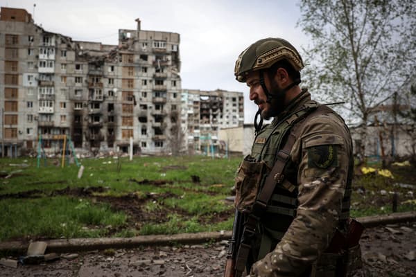 Un militaire ukrainien marche près d'un bâtiment résidentiel endommagé par des tirs d'obus dans la ville de Bakhmout, dans la région de Donetsk, le 23 avril 2023.