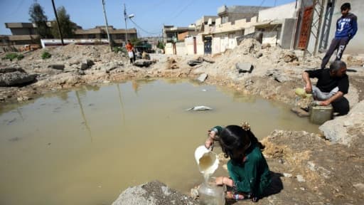 Des habitants de Mossoul remplissent des bidons d'eau, le 6 avril 2017 en Irak