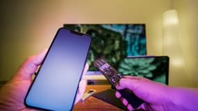 Un smartphone devant une télévision.
