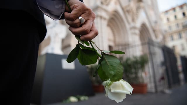 Une personne tient des fleurs près de la basilique Notre-Dame de l'Assomption lors d'une cérémonie organisée pour marquer le premier anniversaire d'un attentat, à Nice, le 29 octobre 2021. 