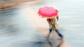 Une femme en train de se réfugier sous un parapluie coloré pour échapper à la pluie (photo d'illustration).