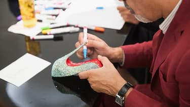 Christian Louboutin sur le point de dédicacer une de ses semelles rouges.