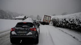 Un camion et des voitures sur une route enneigée, près de La Clusaz, le 23 décembre 2024.