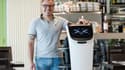 Geoffrey Ruamps, directeur du restaurant le Cap 180, pose avec le robot serveur "Bella" dans son restaurant, à Cieurac, dans le Lot, le 14 mai 2024.