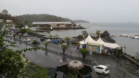 Une femme marche avec un parapluie vers une rue du front de mer de Mamoudzou sur l'île française de Mayotte, dans l'océan Indien, le 8 décembre 2019, où la circulation des véhicules est limitée alors que le cyclone Belna devrait toucher terre.