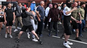 Un manifestant masqué jette une canette de bière en direction de la police anti-émeute à Bristol, dans le sud de l'Angleterre, le 3 août 2024.