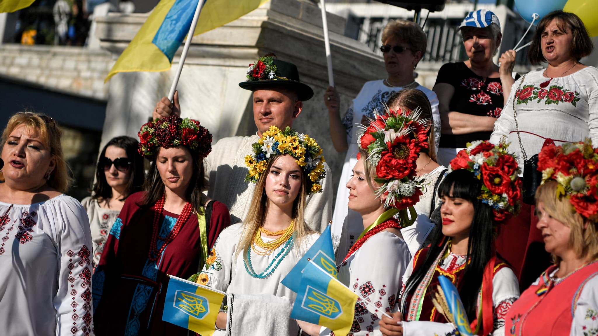 Des Ukrainiens vêtus de vêtements brodés traditionnels écoutent leur hymne national alors qu'ils participent à la célébration de la "Journée Vyshyvanka", une célébration annuelle des traditions folkloriques ukrainiennes, dans les rues d'Athènes le 22 mai 2022.
