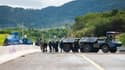 Des gendarmes mobiles sécurisent la zone pendant une opération de nettoyage de la route menant à l'aéroport de Nouméa dans le quartier de Païta, en Nouvelle-Calédonie, le 19 mai 2024