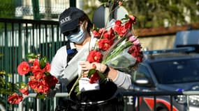Une policière ramasse des fleurs apportées en hommage à Stéphanie Monfermé, le 26 avril 2021 devant l'hôtel de police de Rambouillet (photo d'illustration)
