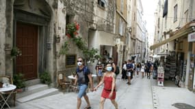Des touristes marchent, équipés de masques, dans une rue de Bonifacio, en Corse, le 5 août 2020