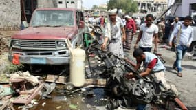 Le 13 mars 2018 à Aden au Yémen, des yéménites inspectent l'épave d'une voiture détruite par l'attentat suicide