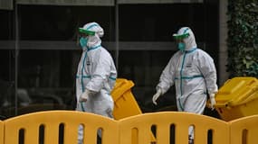 Des travailleurs vêtus de combinaisons de protection, devant l'hôtel dans lequel les enquêteurs de l'OMS se trouvaient en quarantaine jusqu'au 28 janvier 2021.