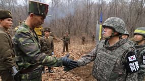 Un soldat sud-coréen et un militaire nord-coréen ayant participé aux travaux sur le point de se serrer la main, sous le regard de leurs camarades.