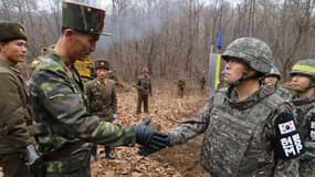 Un soldat sud-coréen et un militaire nord-coréen ayant participé aux travaux sur le point de se serrer la main, sous le regard de leurs camarades.