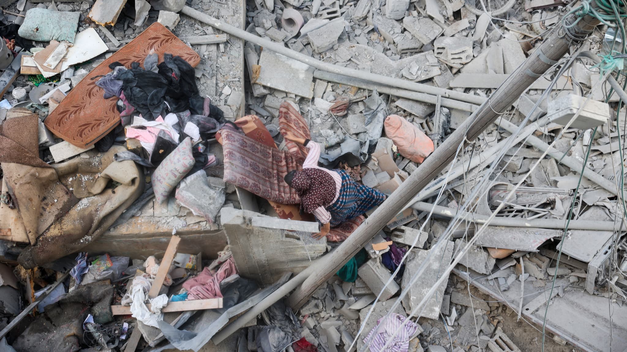 Une femme fouille les décombres de sa maison, détruite par une frappe israélienne, à la recherche d'objets récupérables dans le camp de réfugiés de Nuseirat, au centre de la bande de Gaza (Palestine), le 18 mars 2025.